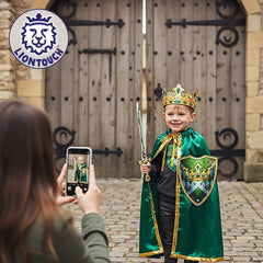 Liontouch Kingmaker Crown worn by a smiling child in a green robe, holding a sword and smartphone in front of a wooden door.
