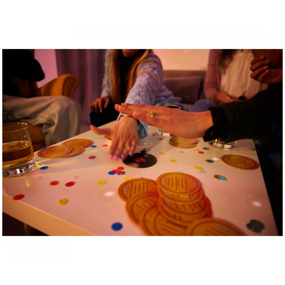 Music-Buster music trivia game being played by friends around a table, featuring colorful cards and a cozy indoor setting.