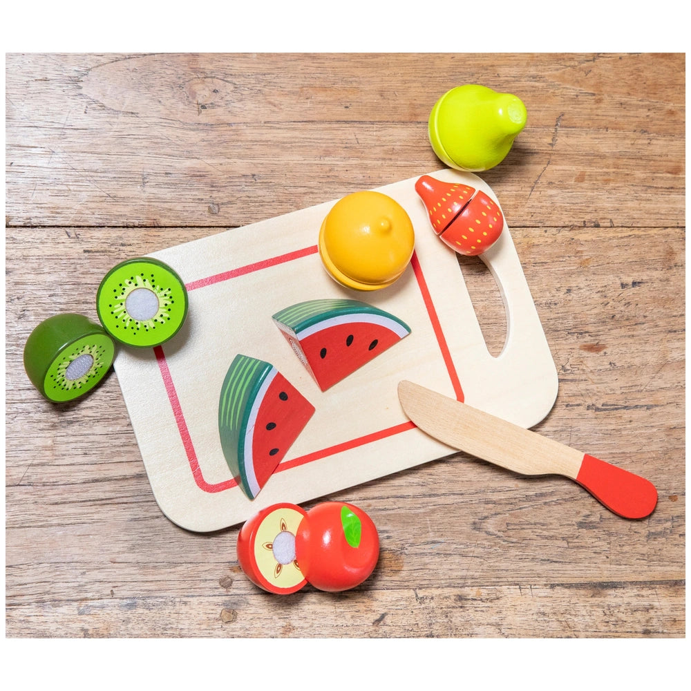 New Classic Toys fruit cutting set on a wooden cutting board, featuring various colorful plastic fruits arranged neatly.
