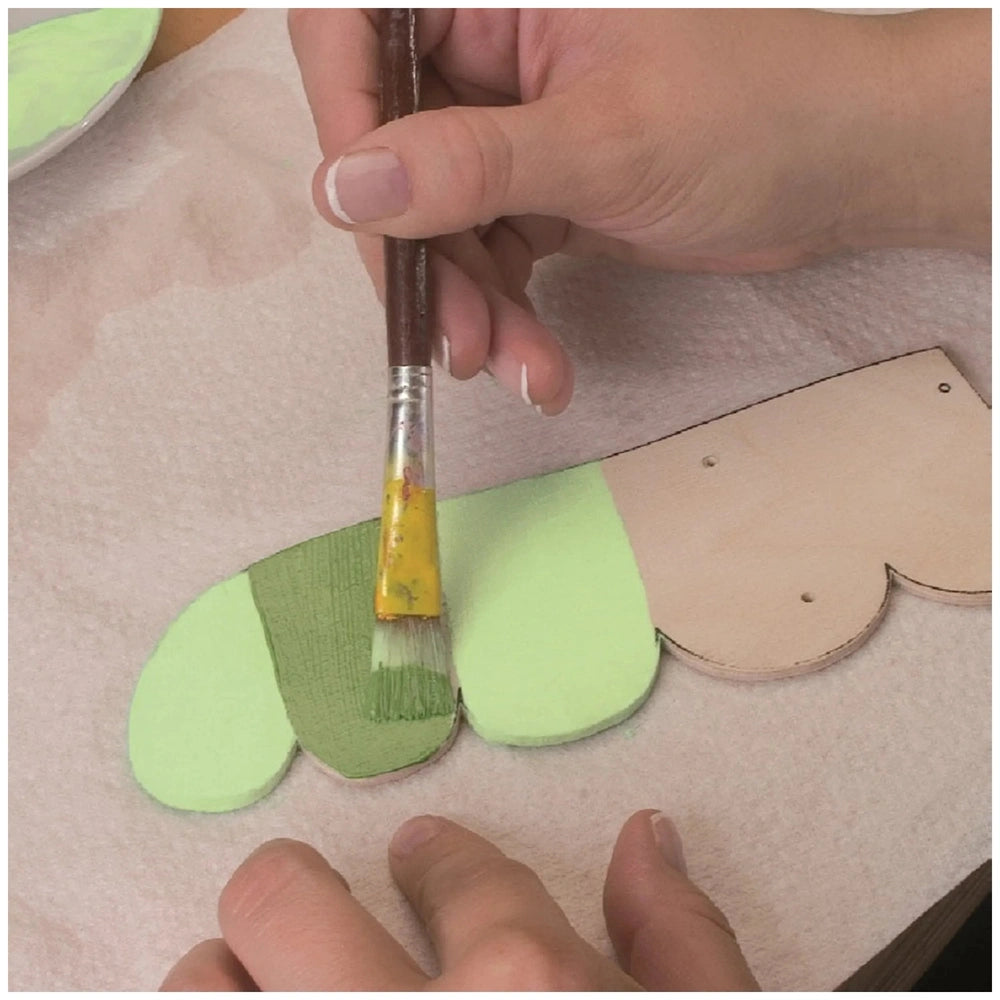 Hand painting wooden craft with light green paint using a brush, showcasing Prebaro Fretwork tool use.