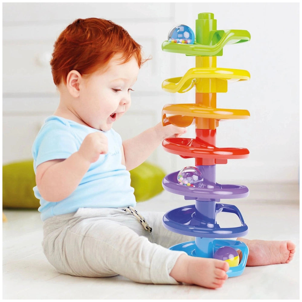 Quercetti Spiral Tower baby activity toy with colorful handles and clear domes, while a child in a light blue top plays.