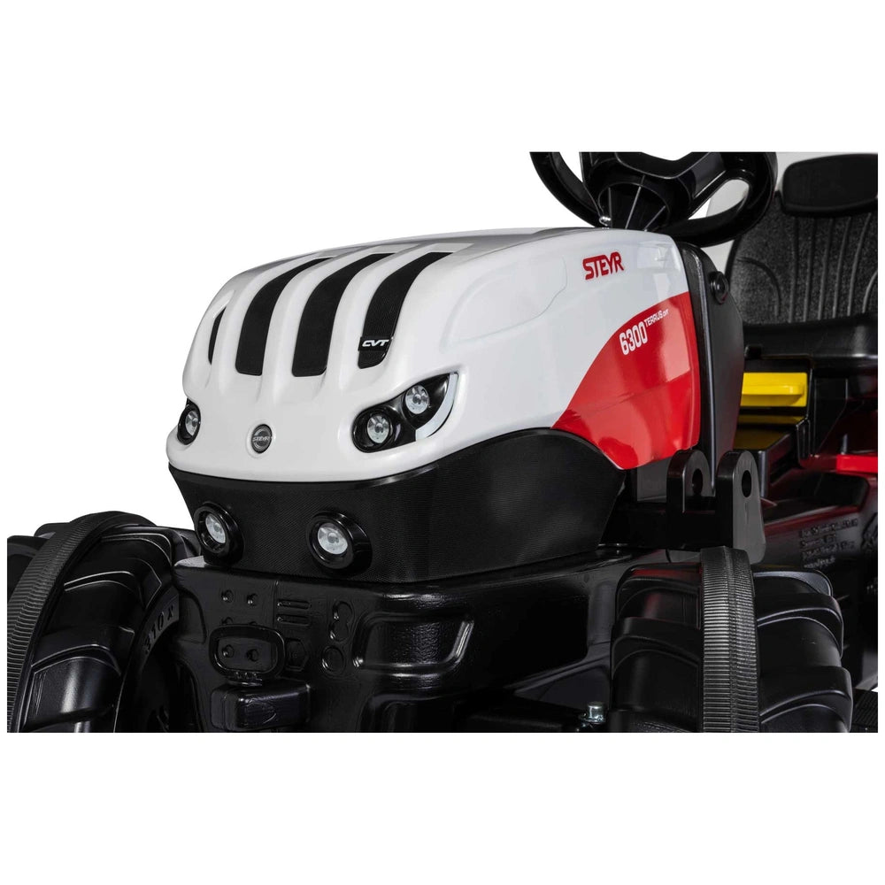 Rollyfarmtrac Premium II Steyr 6300 Terrus CVT features a black, white, and red control panel with buttons and a steering whe