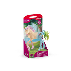 Marshmallow Unicorn Foal toy in pink packaging with a glossy finish, featuring a green horn and standing on grass.