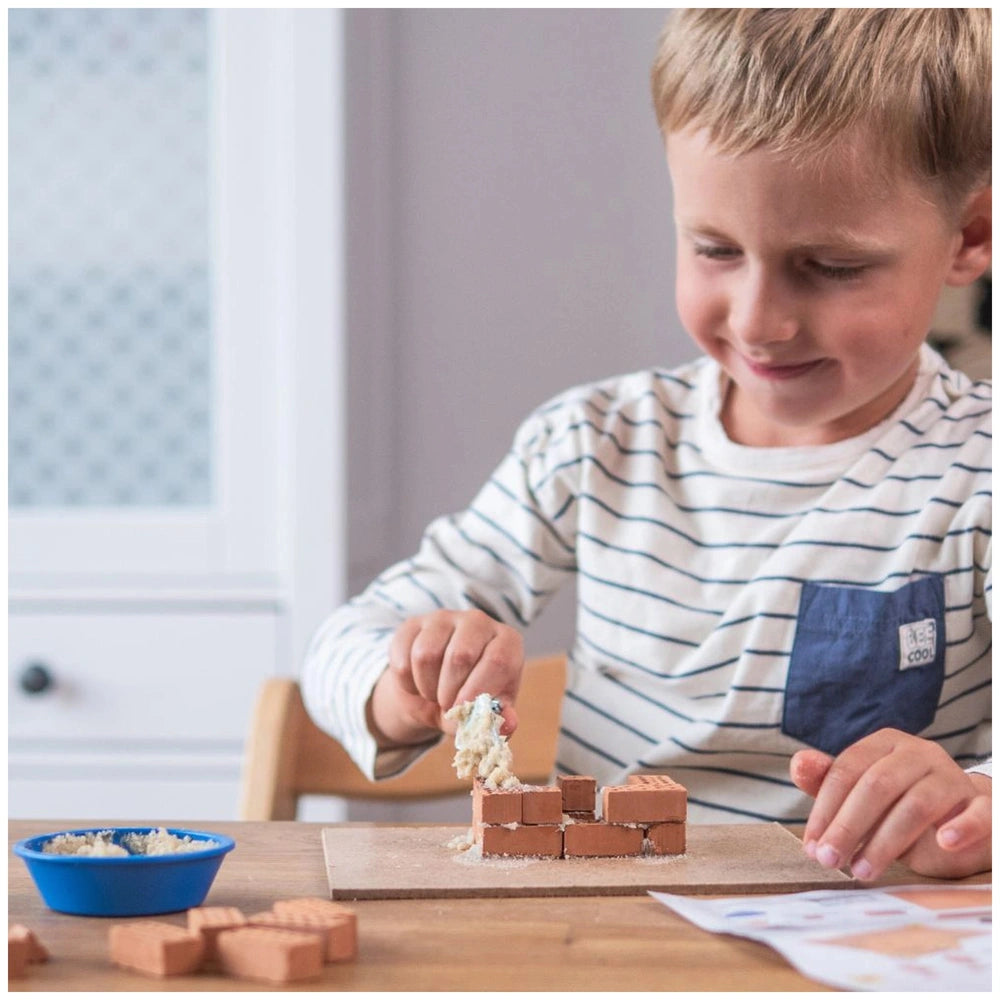 Teifoc doghouse building set with a smiling child in a striped shirt engaged in block construction at a wooden table.