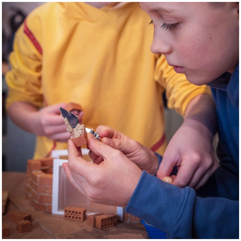 Teifoc garden house set with children using colorful Lego bricks and scissors to create and modify their build indoors.