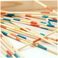 Teorema Mikado stick game features colorful wooden sticks in red, blue, and yellow, arranged haphazardly on a light surface.