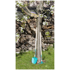 Theo Klein Bosch Garden Gardener Set with blue shovel and yellow-purple tool on grass near flowering tree and wooden fence.