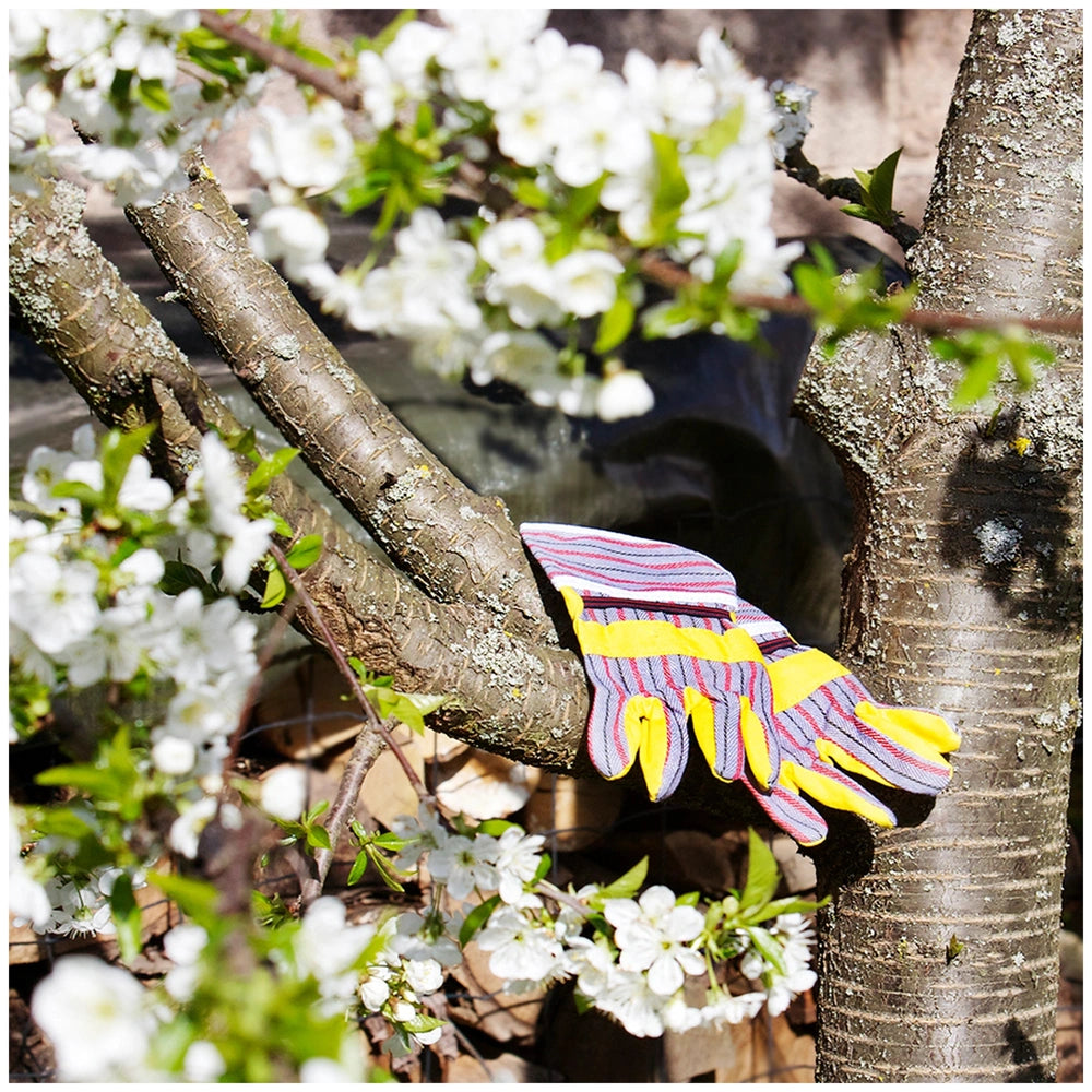 Theo Klein Bosch Garden Gardener Set with gloves on a tree branch amidst green foliage and a brown tree trunk.