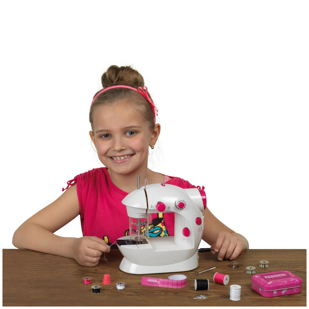 a young girl with a pink headband using a white Theo Klein kids sewing machine with multiple colorful spools on a wooden tabl